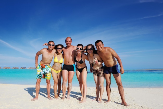 un gruppo di giovani felici si divertono e si rallegrano sulla spiaggia di sabbia bianca in una bella giornata d'estate