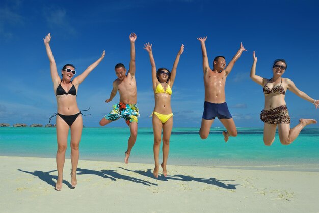 un gruppo di giovani felici si divertono e si rallegrano sulla spiaggia di sabbia bianca in una bella giornata d'estate