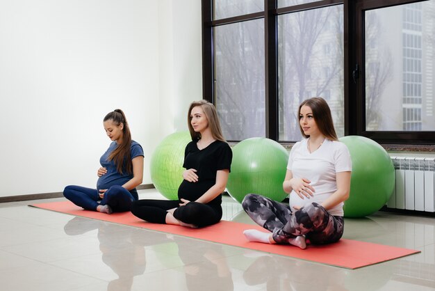 Un gruppo di giovani ragazze incinte fa yoga e sport su stuoie al coperto. Uno stile di vita sano