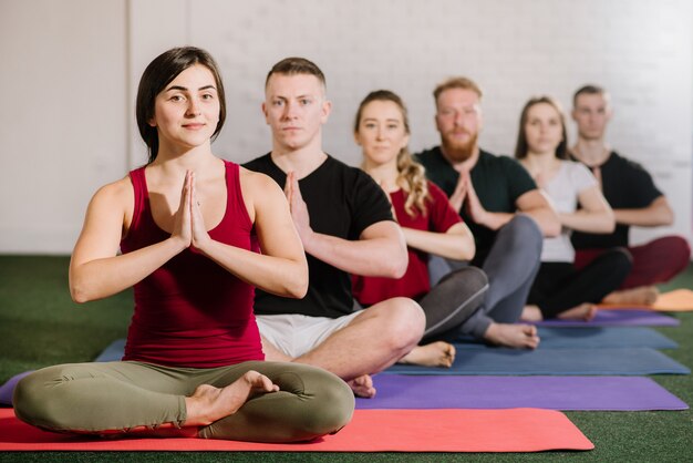 Un gruppo di giovani seduti in posa yoga uno dietro l'altro