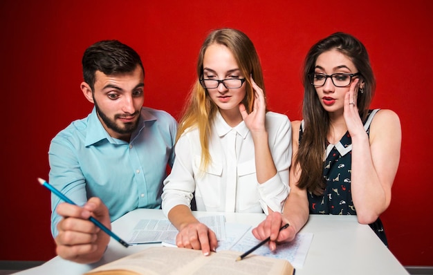 Un gruppo di giovani studenti attraenti ha una discussione amichevole sorpresa concetto di studente di lavoro di squadra di reazione