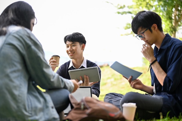 Un gruppo di giovani studenti universitari asiatici intelligenti che lavorano insieme al loro progetto di gruppo nel parco