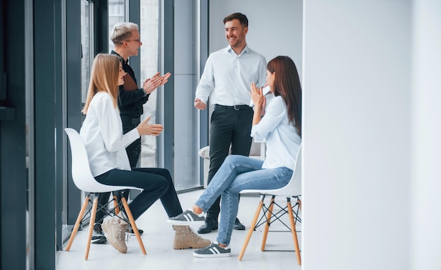 Un gruppo di giovani team di successo lavorano e comunicano insieme all'interno dell'ufficio vicino alle finestre