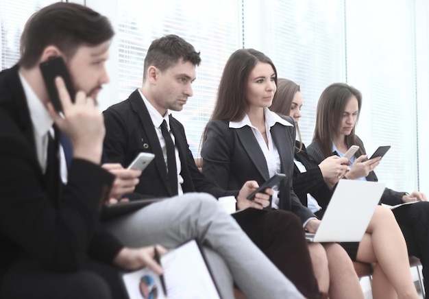 Un gruppo di giovani uomini d'affari utilizza laptop e smartphone mentre è seduto nella hall dell'ufficio