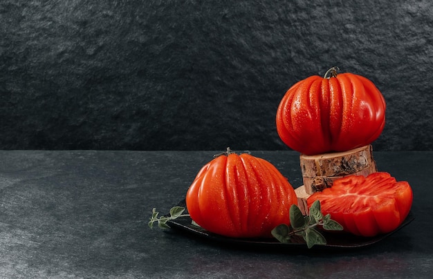 Un gruppo di grossi pomodori Costoluto con origano su sfondo grigio spazio per il testo