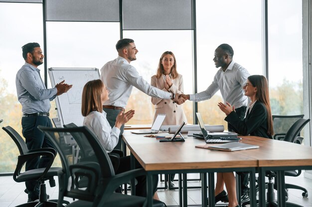 Un gruppo di impiegati si stringe la mano in un ufficio