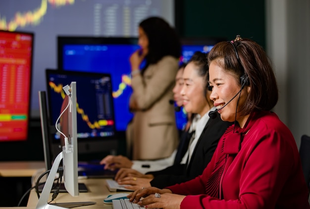 Un gruppo di operatori del servizio clienti donne asiatiche indossa cuffie microfoniche che sorridono di fronte ogni giorno