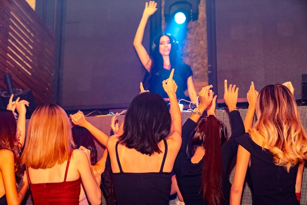 Un gruppo di persone balla in discoteca al ritmo della musica del DJ sul palco