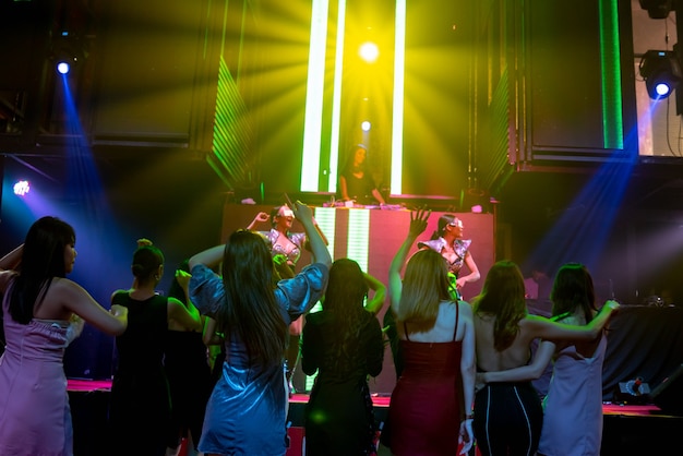 Un gruppo di persone balla in discoteca night club al ritmo della musica di DJ sul palco