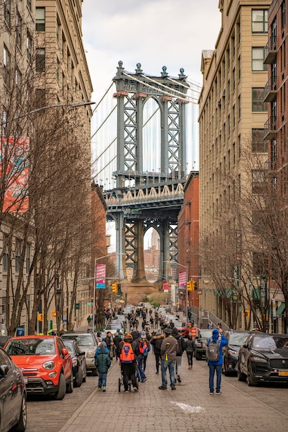 Un gruppo di persone cammina lungo una strada sotto un ponte.