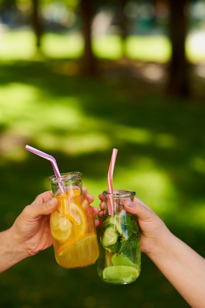 Un gruppo di persone festeggia con cocktail di succo di disintossicazione sullo sfondo della natura verde