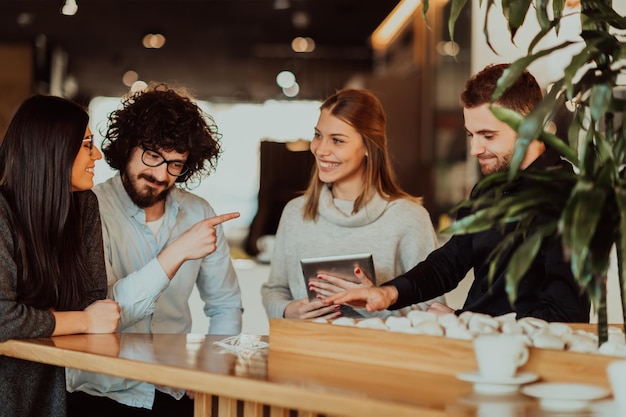 Un gruppo di persone in pausa caffè utilizza laptop, tablet e smartphone mentre discute di nuovi progetti di business. concetto di affari.