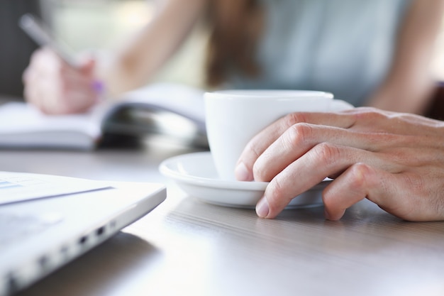 Un gruppo di persone in un bar comunica con una tazza di caffè