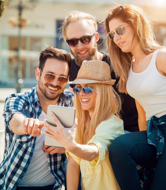 Un gruppo di quattro amici felici che prendono selfie