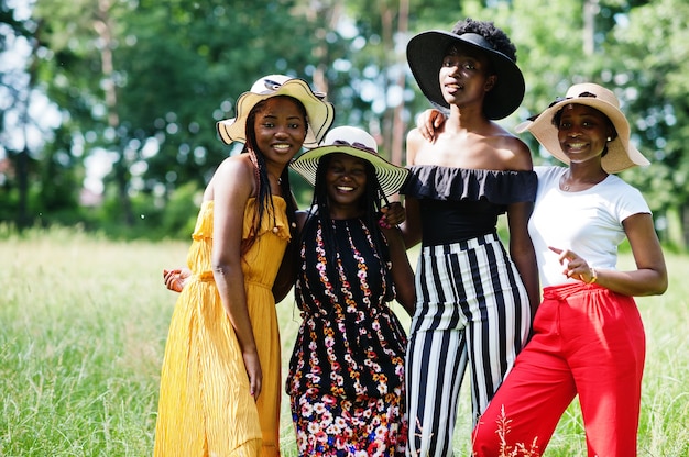 Un gruppo di quattro donne bellissime indossano cappelli estivi che trascorrono del tempo all'erba verde nel parco