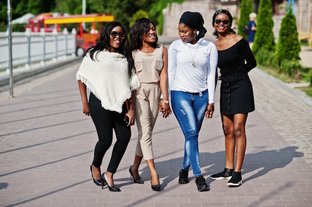 Un gruppo di quattro donne che camminano alla città il giorno soleggiato