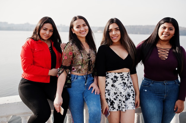 Un gruppo di quattro ragazze felici e graziose del latino dall'Ecuador ha posato contro il lato del lago.