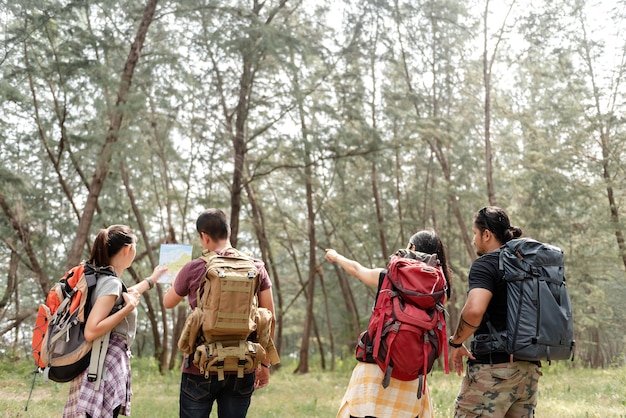Un gruppo di quattro viaggiatori con lo zaino sta progettando una passeggiata nella foresta.