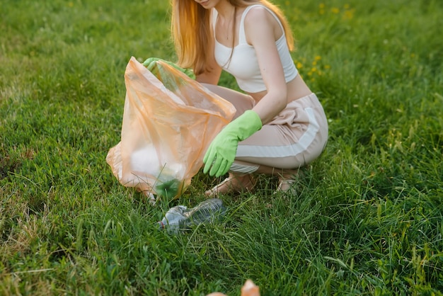 Un gruppo di ragazze con bambini al tramonto è impegnato nella raccolta dei rifiuti nel parco. Cura dell'ambiente, riciclaggio.