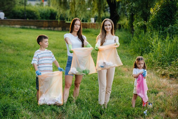 Un gruppo di ragazze con bambini al tramonto è impegnato nella raccolta dei rifiuti nel parco. Cura dell'ambiente, riciclaggio.