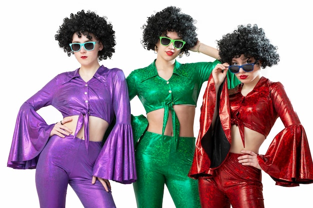 Un gruppo di ragazze della discoteca con parrucche afroamericane e costumi colorati su uno sfondo bianco. Moda degli anni settanta e ottanta.