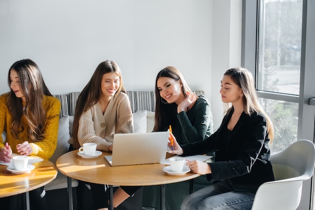 Un gruppo di ragazze si siede in un ufficio davanti ai computer e discute dei progetti. Comunicazione e formazione online.