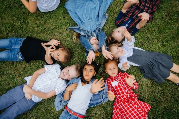 Un gruppo di scolari giace sull'erba in cerchio e si diverte. Infanzia felice.