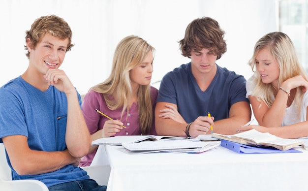 Un gruppo di studenti seduti insieme mentre studiano tutti come sorrisi