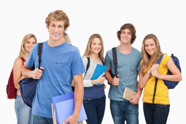 Un gruppo di studenti universitari sorridenti guarda nella telecamera come un uomo si trova di fronte