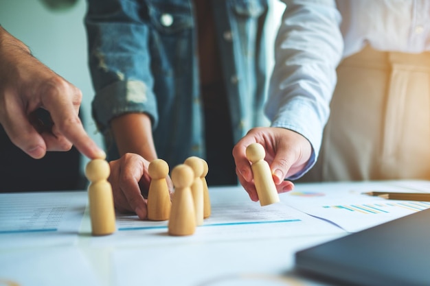 Un gruppo di team aziendali di brainstorming e strategia di pianificazione insieme a persone di legno in una riunione