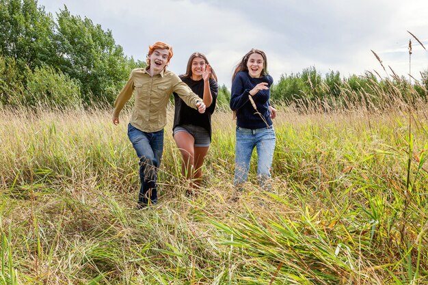 Un gruppo di tre amici ragazzo e due ragazze che corrono e si divertono insieme all'aperto