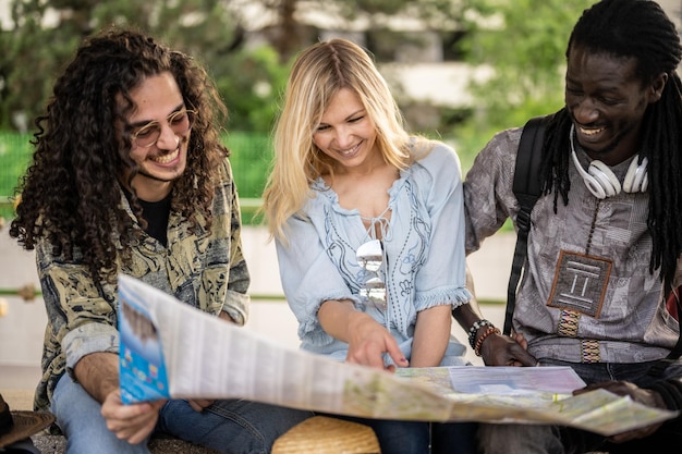 Un gruppo di tre persone in viaggio verso la stazione controlla sulla mappa il proprio itinerario