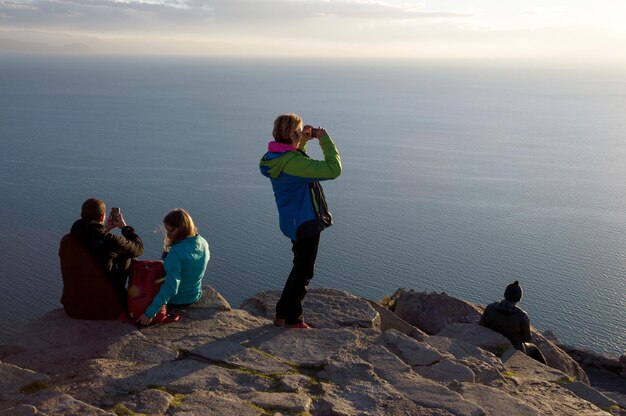 Un gruppo di turisti che guardano e registrano il tramonto al lago Titicaca