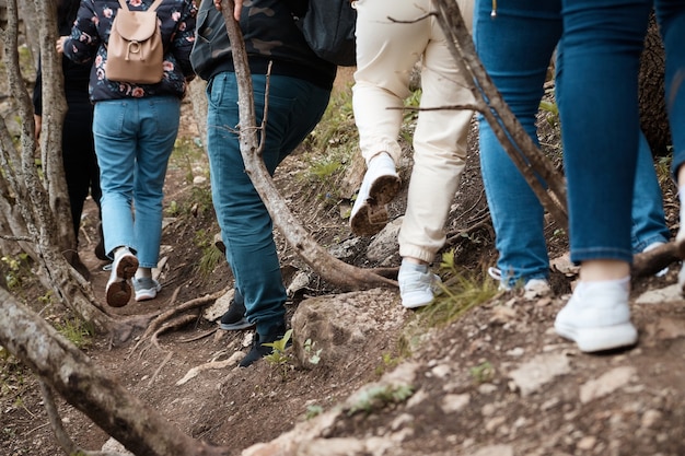 Un gruppo di turisti fa un'escursione su una strada forestale, foto ravvicinata di gambe, gambe in movimento