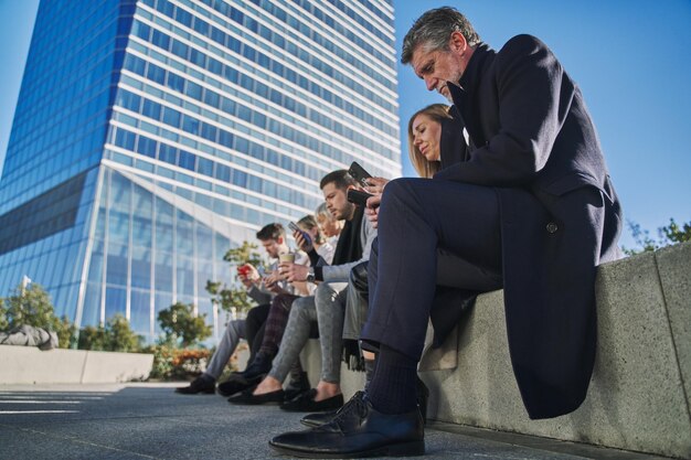 un gruppo di uomini d'affari che usano il loro smartphone mentre fanno una pausa da un giorno in ufficio