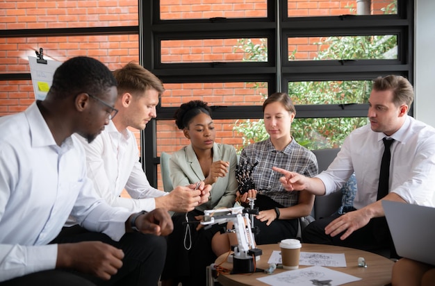 Un gruppo di uomini d'affari diversi che lavorano insieme in ufficio a brainstorming sul robot a mano