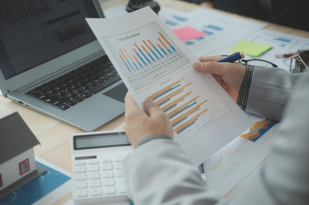 Un gruppo di uomini d'affari fiduciosi indica grafici e grafici per analizzare l'utile netto del conto di bilancio dei dati di mercato per pianificare nuove strategie di vendita per aumentare la capacità produttiva