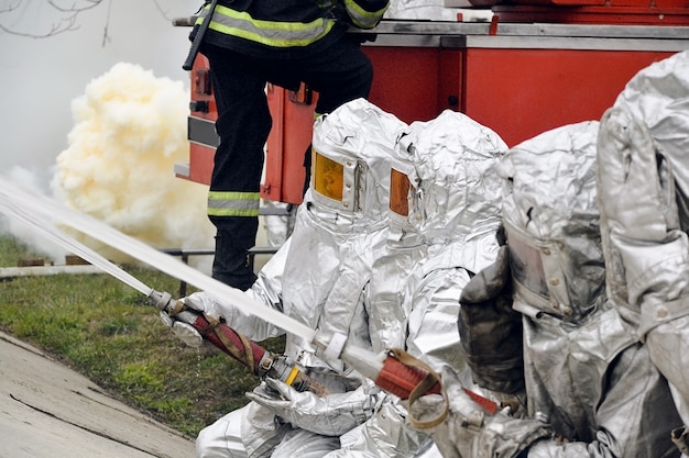 Un gruppo di vigili del fuoco che attacca un incendio con acqua e schiuma. vigili del fuoco funziona