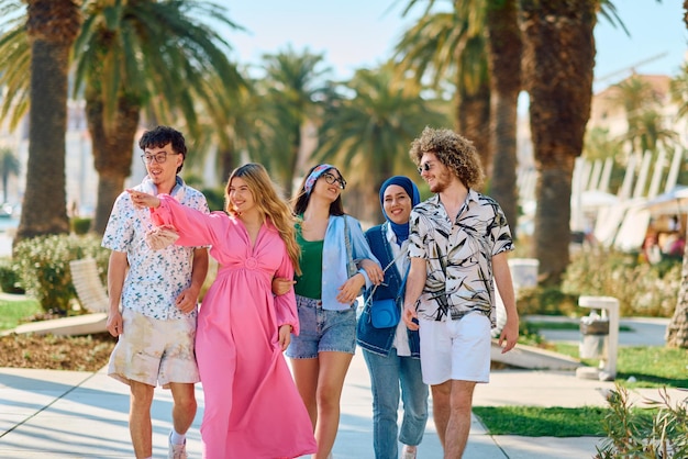 Un gruppo diversificato di turisti vestiti con abiti estivi passeggiano per la città turistica con ampi