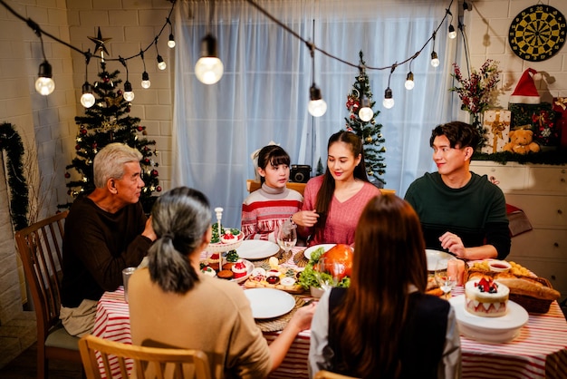 Un gruppo felice e allegro di una famiglia asiatica che parla e sorride durante la cena di Natale