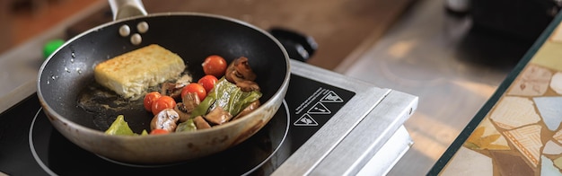 Un gustoso formaggio fritto con verdure stufate si cucina sulla padella nella cucina del ristorante