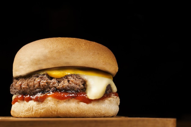 un hamburger su una tavola di legno con uno sfondo nero.