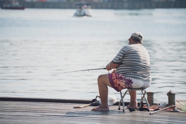 Un hobby di pesca, un pescatore maschio seduto sull'argine del fiume della città e che cattura pesce