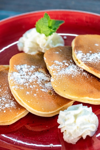 Un'immagine di pancake in stile americano appena fatti tagliati con frutta fresca e crema