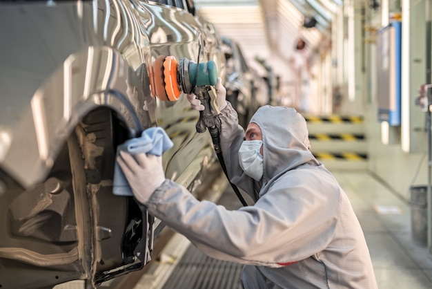 Un impiegato dell'officina di verniciatura di uno stabilimento automobilistico lucida la superficie verniciata.