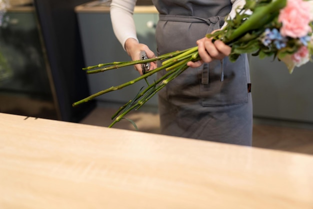 Un impiegato di un negozio di fiori taglia i fiori freschi prima di farne un bouquet