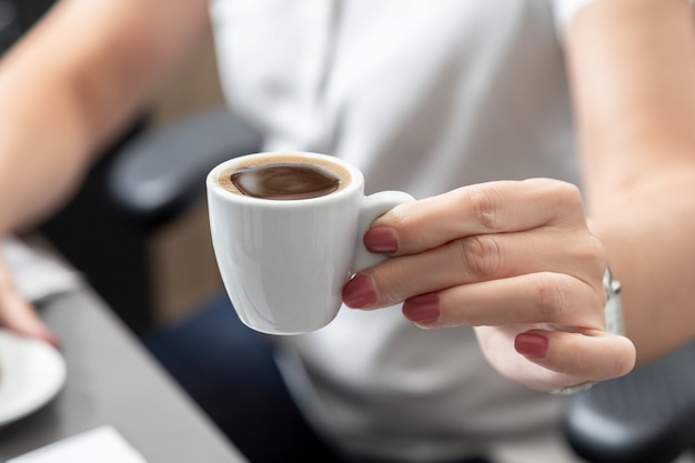 Un impiegato tiene in mano una tazza bianca di caffè aromatizzato