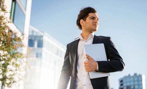 Un imprenditore maschio è in piedi con in mano un laptop Un broker intelligente è un investitore