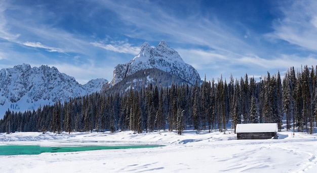 Un'incredibile capanna al centro di un grande lago pieno di neve con grandi montagne sullo sfondo