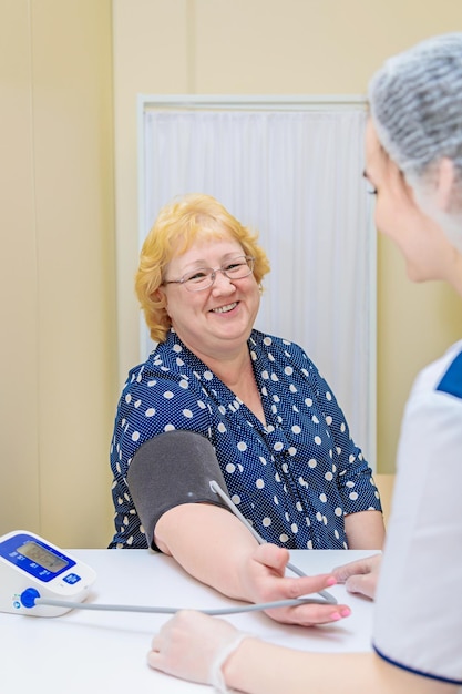 Un'infermiera in una policlinica misura la pressione sanguigna di una donna con un dispositivo sanitario